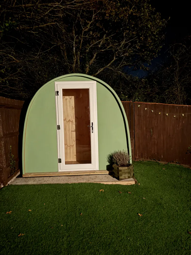 Deb Read's green Dory Pod home office in her garden in the evening