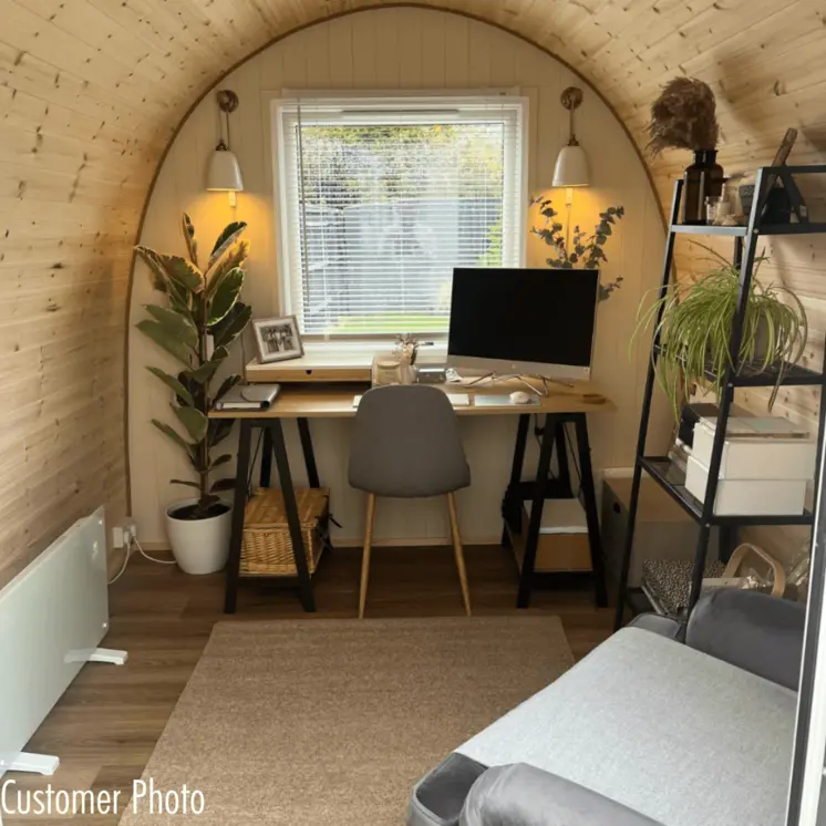A cosy and inviting garden office setup within a Hully Pod, surrounded by lush greenery.  