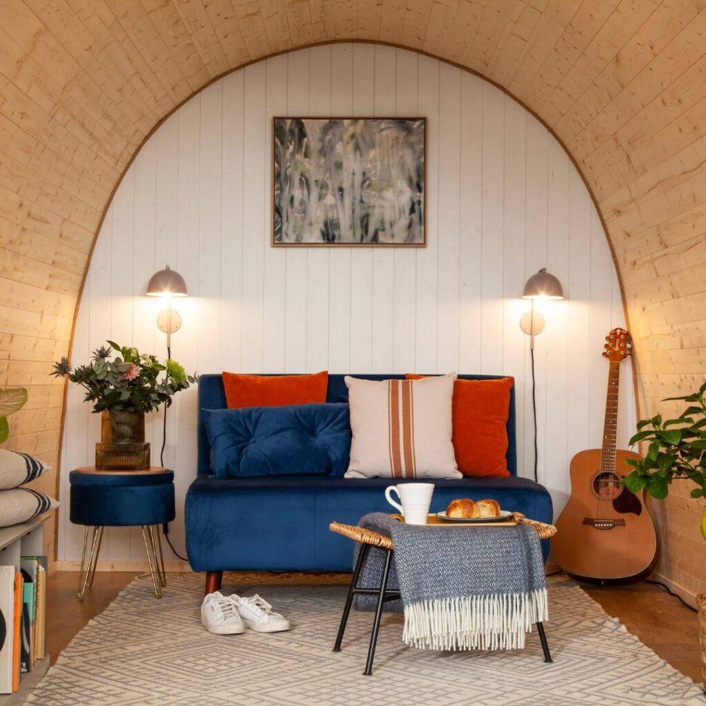 Start a glamping business in the U.K. with garden rooms: Image of Hully Glamping Pod with futon, tea, and decor