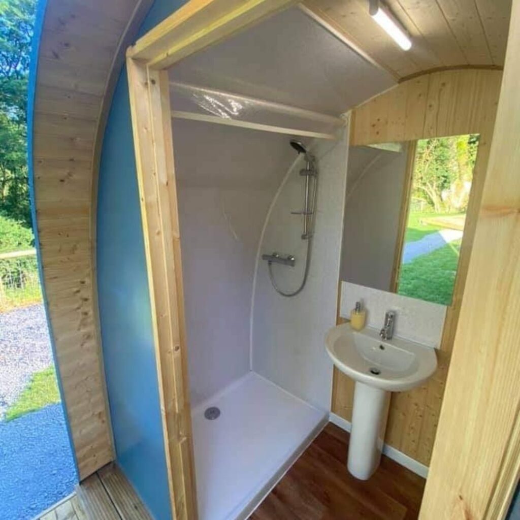 Starting a Glamping Business: Standard Campsite Size Outdoor Pods | Image Description: A blue wetroom Pod with shower and sink